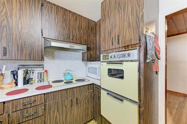 kitchen featuring backsplash, hardwood / wood-style floors, and white appliances