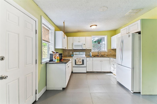 kitchen with white appliances, white cabinets, and a wealth of natural light