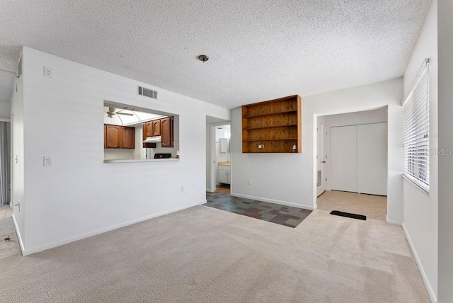 unfurnished living room with a textured ceiling, ceiling fan, and light colored carpet