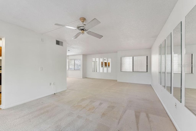 carpeted empty room with a textured ceiling, ceiling fan, and a healthy amount of sunlight