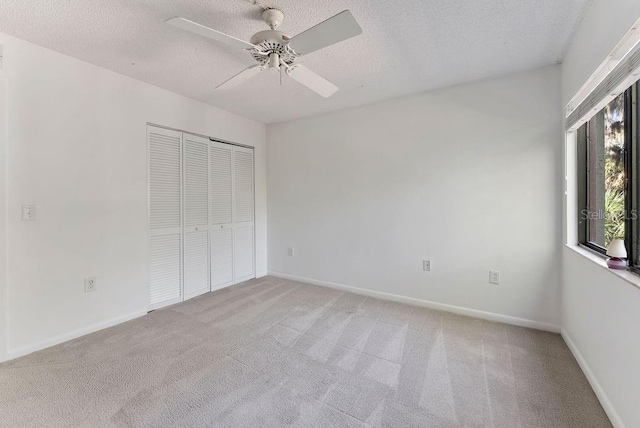 unfurnished bedroom with a closet, light carpet, a textured ceiling, and ceiling fan