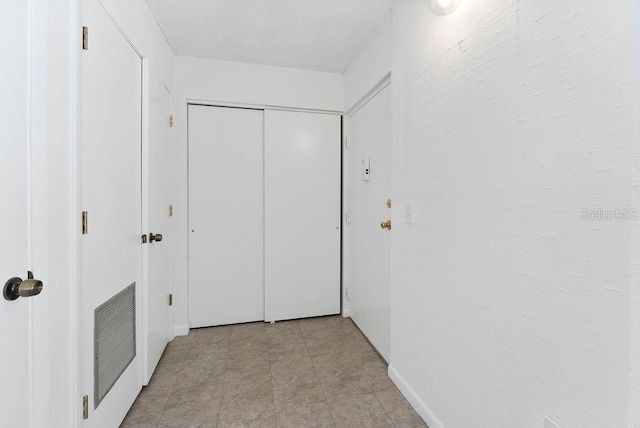 hall featuring a textured ceiling and light tile flooring