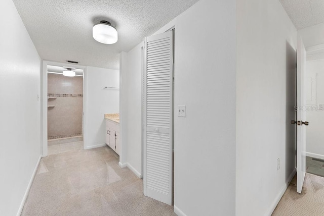 corridor featuring light carpet and a textured ceiling