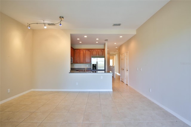 interior space with kitchen peninsula, appliances with stainless steel finishes, light tile patterned floors, and sink