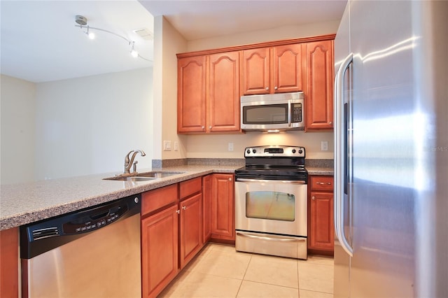 kitchen with kitchen peninsula, appliances with stainless steel finishes, light tile patterned floors, and sink