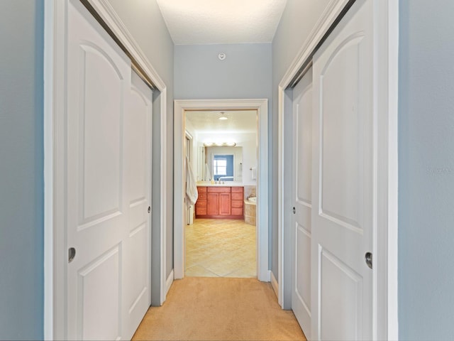 hallway featuring light carpet and a textured ceiling