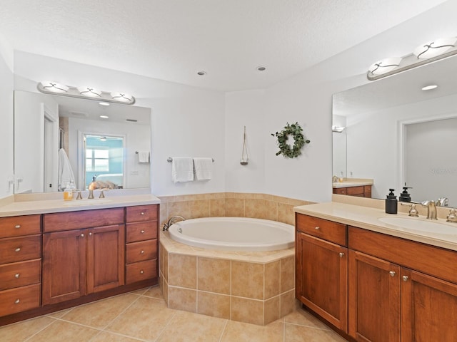 bathroom featuring vanity, a textured ceiling, tile patterned flooring, and tiled bath