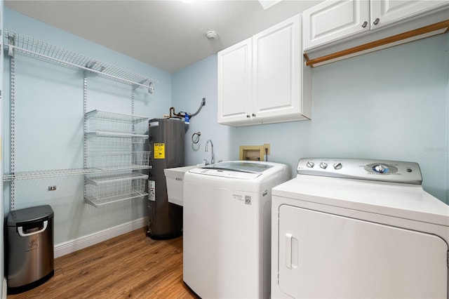 washroom featuring water heater, cabinets, light wood-type flooring, and washing machine and clothes dryer