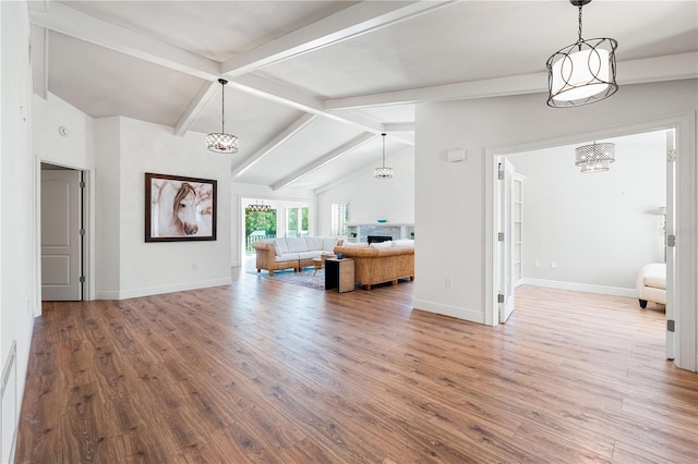 unfurnished living room with hardwood / wood-style flooring, lofted ceiling with beams, and a stone fireplace