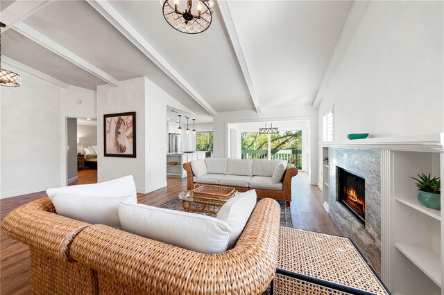 living room featuring a high end fireplace, beam ceiling, hardwood / wood-style flooring, and an inviting chandelier