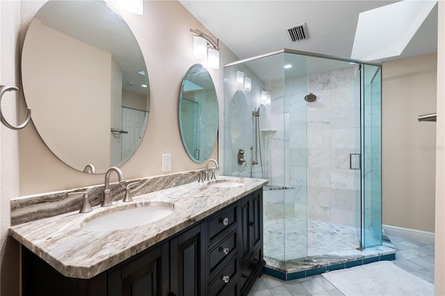 bathroom with vanity, a skylight, tile patterned floors, and a shower with door