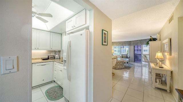 interior space with white appliances, white cabinetry, ceiling fan, and light tile floors