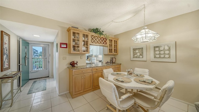 tiled dining area featuring an inviting chandelier and a textured ceiling