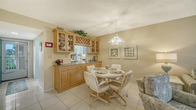 kitchen with a textured ceiling, light tile floors, and light stone counters