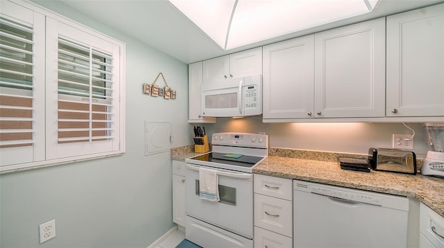 kitchen featuring white appliances, light stone countertops, and white cabinetry