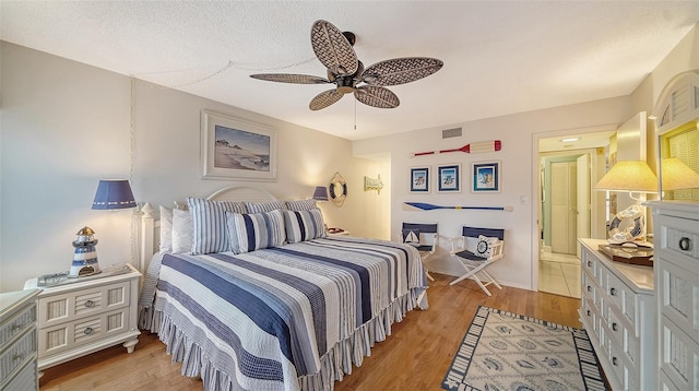 bedroom featuring a textured ceiling, ceiling fan, and light wood-type flooring