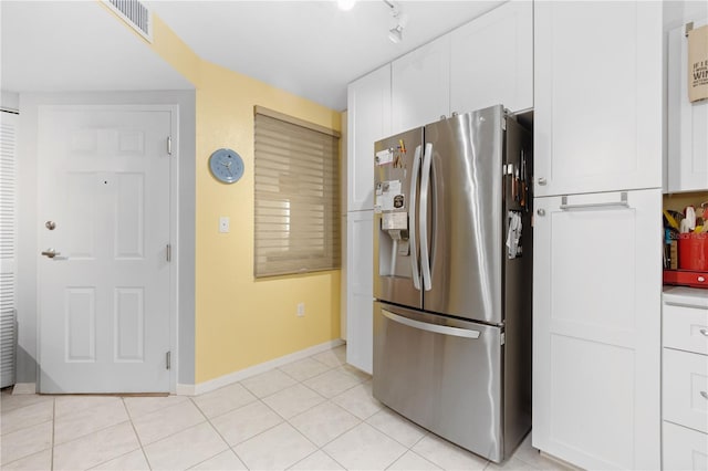 kitchen featuring light tile patterned floors, stainless steel fridge with ice dispenser, and white cabinetry