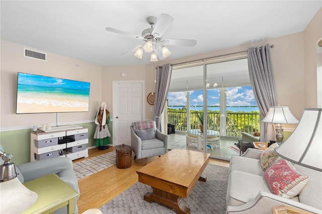 living room with ceiling fan, light hardwood / wood-style flooring, and a water view