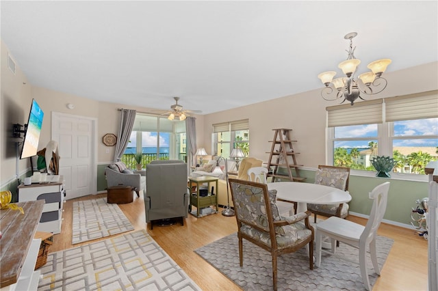 dining room featuring ceiling fan with notable chandelier, a wealth of natural light, and light hardwood / wood-style floors