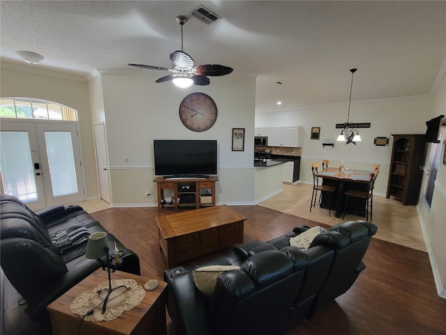 living room with ceiling fan with notable chandelier, a textured ceiling, light hardwood / wood-style flooring, and ornamental molding