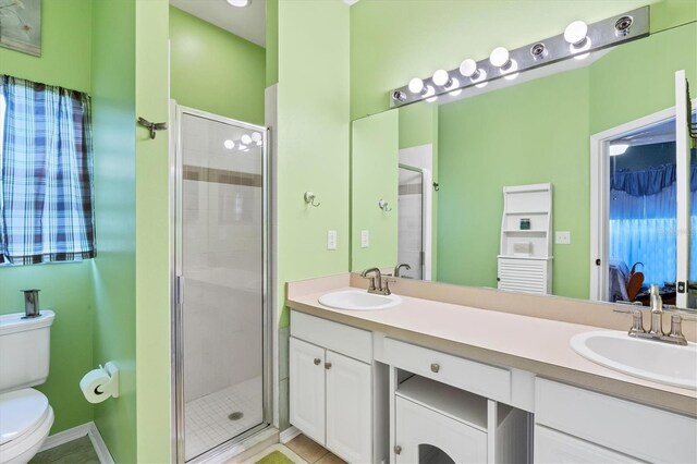 bathroom with tile patterned floors, vanity, toilet, and a shower with door