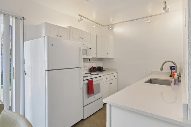 kitchen featuring rail lighting, a wealth of natural light, white appliances, white cabinets, and sink