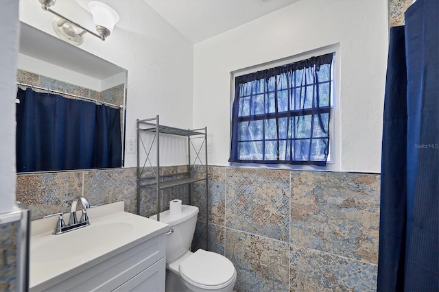 bathroom featuring tile walls, toilet, oversized vanity, and an inviting chandelier