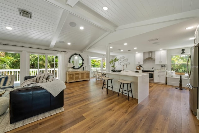 living room featuring vaulted ceiling with beams, sink, and hardwood / wood-style floors