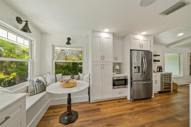 kitchen featuring stainless steel fridge, white cabinetry, hardwood / wood-style floors, and wine cooler