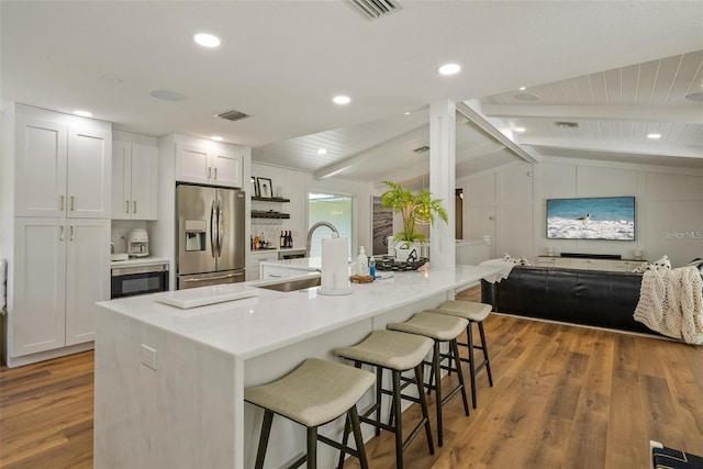 kitchen with sink, white cabinetry, hardwood / wood-style flooring, and stainless steel fridge with ice dispenser