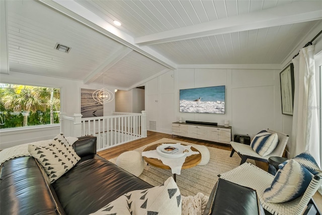 living room featuring a notable chandelier, lofted ceiling with beams, and light wood-type flooring