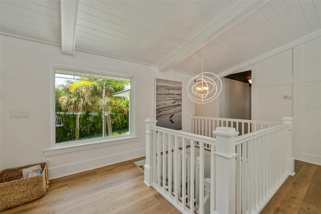 hallway with lofted ceiling with beams, light hardwood / wood-style flooring, and a notable chandelier