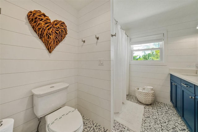 bathroom featuring wood walls, tile patterned floors, toilet, and vanity