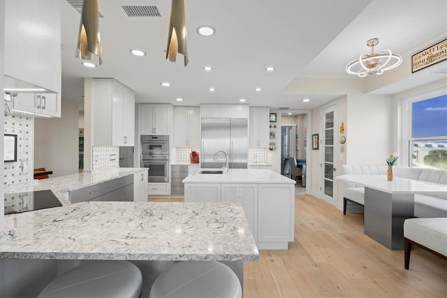 kitchen with appliances with stainless steel finishes, light hardwood / wood-style floors, white cabinetry, and sink