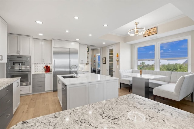 kitchen with hanging light fixtures, light hardwood / wood-style flooring, decorative backsplash, appliances with stainless steel finishes, and ornamental molding