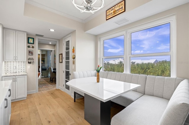 dining room with light hardwood / wood-style floors and crown molding