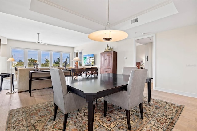 dining room featuring a tray ceiling, ceiling fan, light hardwood / wood-style flooring, and ornamental molding