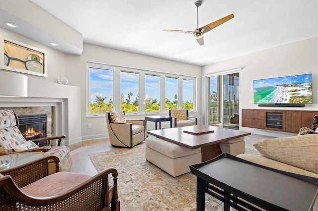 living room featuring a fireplace, light hardwood / wood-style flooring, and ceiling fan