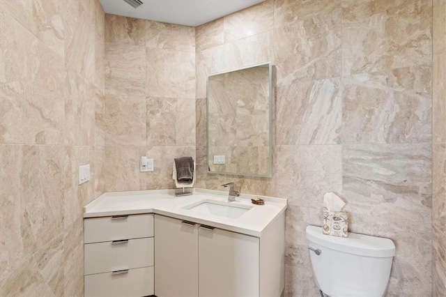 bathroom featuring vanity, toilet, and tile walls