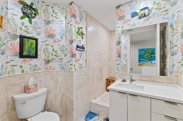 bathroom with vanity, toilet, and tile walls