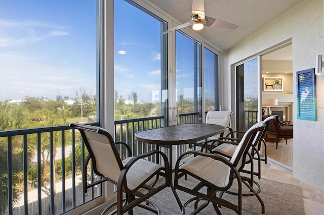 sunroom / solarium featuring ceiling fan and a fireplace