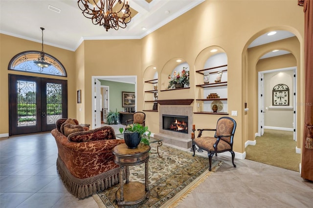 foyer featuring light tile patterned floors, a tile fireplace, a towering ceiling, ornamental molding, and french doors