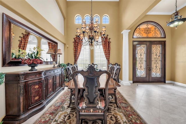 tiled dining room with an inviting chandelier, french doors, a high ceiling, and ornate columns