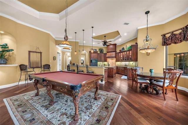 recreation room with billiards, ornamental molding, ceiling fan, a tray ceiling, and dark wood-type flooring