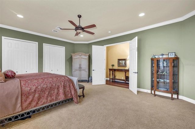 carpeted bedroom featuring ceiling fan, ornamental molding, and two closets