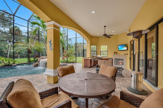 view of patio featuring pool water feature, an outdoor kitchen, an in ground hot tub, ceiling fan, and a fireplace