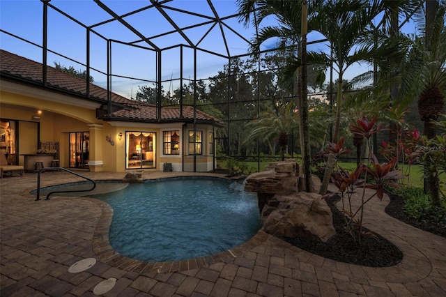 pool at dusk with a patio and a lanai