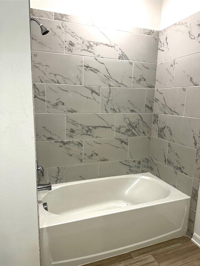 bathroom featuring hardwood / wood-style flooring and tiled shower / bath combo