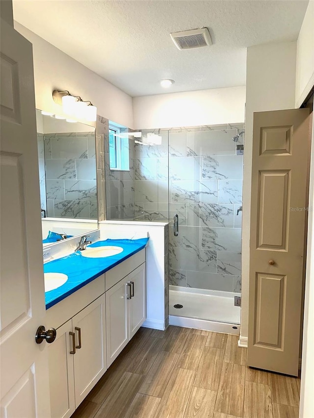 bathroom featuring vanity, a textured ceiling, and an enclosed shower