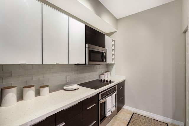 kitchen with decorative backsplash, appliances with stainless steel finishes, dark brown cabinets, light tile patterned floors, and white cabinetry